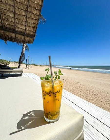 Drink de maracujá com hortelã, servido com vista para a praia.