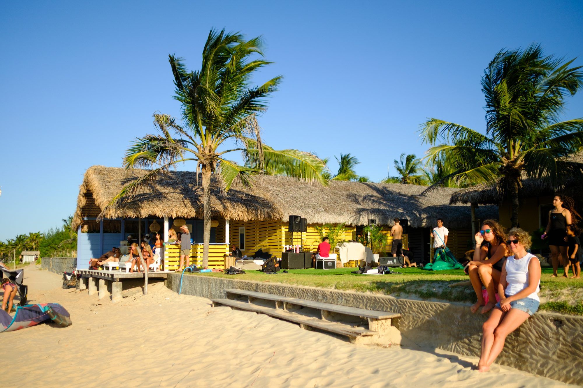Vista de la fachada de Cabana do Kite desde la playa, techo de paja y palmeras.